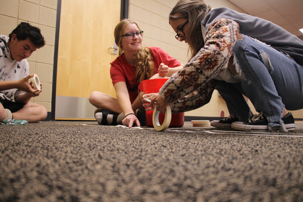 EHS students tape penny trails on the floor to see which class collected the most inches.